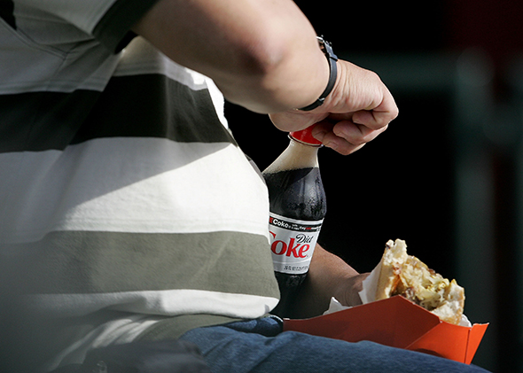 A man opens a bottle of Diet Coke as he eats before the start of the baseball game with the San Francisco Giants and the Atlanta Braves at AT&T Park July 24, 2007 in San Francisco, California.