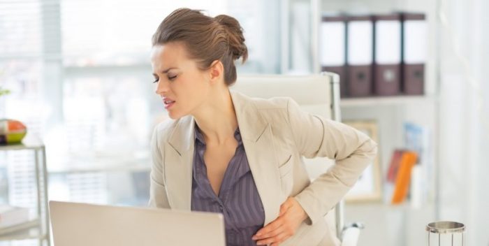 Business woman with stomach ache in office