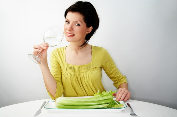 young woman having her breakfast with water and celery