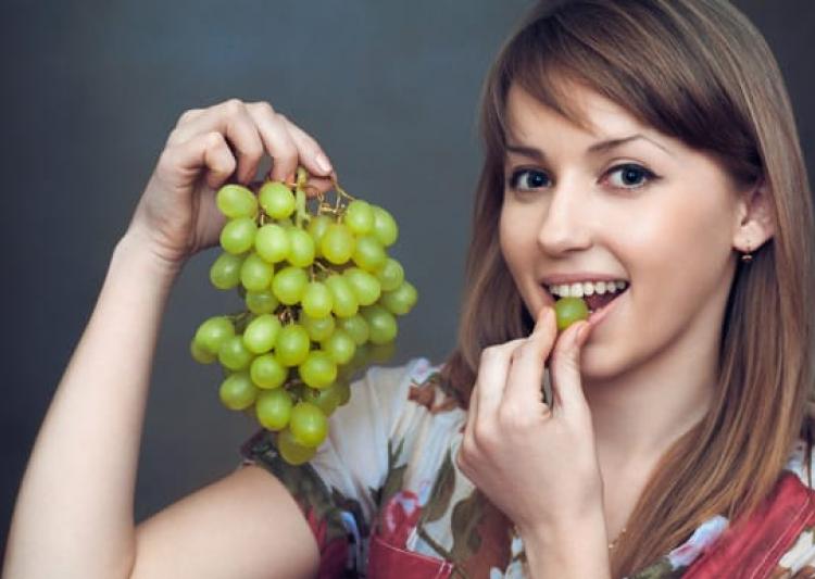 young-woman-eating-green-grapes-1486270425