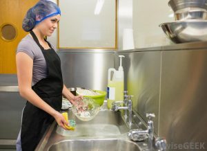 woman-in-black-apron-and-cap-washing-dishes