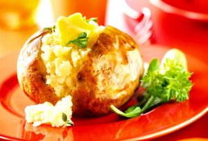 Plain jacket potato with butter on red plate